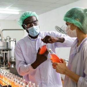 Quality control engineer work with female worker. Workers in the factory write down notes about bottles or gallons before send to customers. Inspection quality control in food factory.