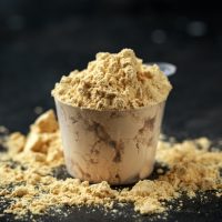 Scoop of Pea Vegan protein powder on dark rustic background. Sport nutrition.